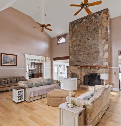 Spacious living area features a stunning stone fireplace and large windows, perfect for natural light.