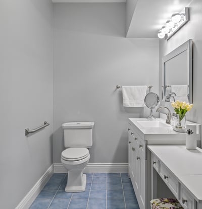 Bright and functional bathroom featuring modern fixtures, ample storage, and sleek blue tile flooring.