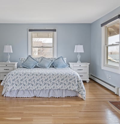 Spacious master bedroom featuring cozy decor, large windows, and a classic brick fireplace for warmth.