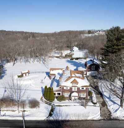 This expansive property features a beautiful home surrounded by lush trees and serene winter landscapes.