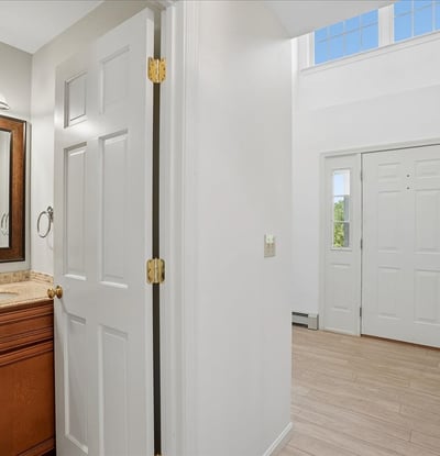 Inviting entryway with dual doors, showcasing bright natural light and a convenient half bath for guests.