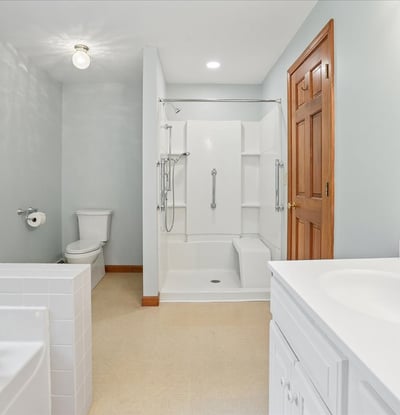 This spacious bathroom features modern fixtures, ample natural light, and a practical layout for everyday use.