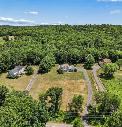Spacious property surrounded by lush woodland, featuring multiple homes and expansive open space for various uses.