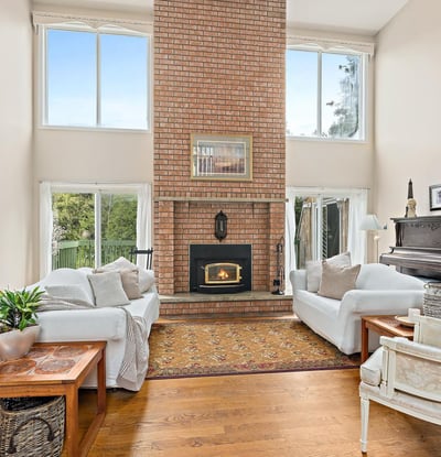 Bright, inviting living space features a striking brick fireplace and large windows, perfect for relaxed gatherings.