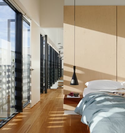 Chic modern bedroom featuring floor-to-ceiling windows, wooden floors, and contemporary design elements for stylish living.