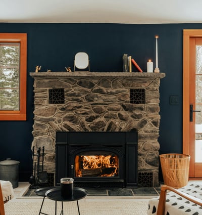 Cozy living area featuring a stone fireplace, large windows, and direct access to a snowy outdoor space.