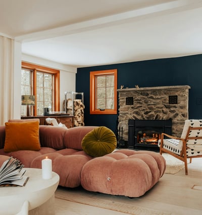 Cozy living room featuring a unique stone fireplace, modern furniture, and large windows for natural light.