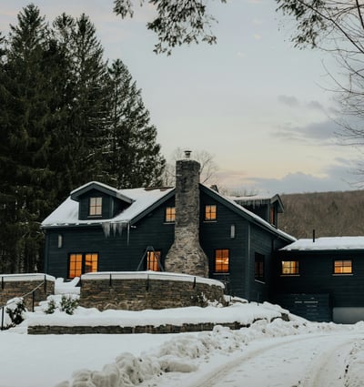 Discover this beautiful mountain retreat, featuring a stone chimney and picturesque winter landscape, perfect for cozy getaways.