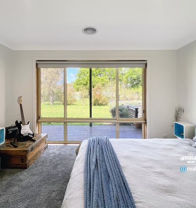 Bright bedroom featuring a large window with garden views, complemented by modern furnishings and cozy atmosphere.