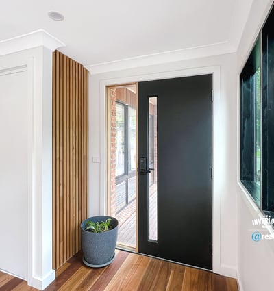 Contemporary entryway featuring a sleek front door and natural light enhancing the warm wooden floors.