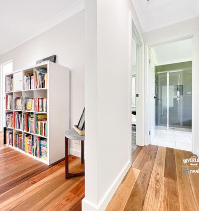 Bright and inviting interior featuring wooden floors, a spacious hallway, and a versatile bookshelf area.