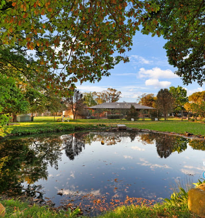 Expansive outdoor space featuring a tranquil pond, surrounded by lush greenery and scenic views.