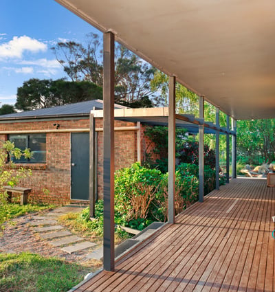 Spacious covered porch leads to a well-maintained garden, offering a welcoming entry to this unique property.