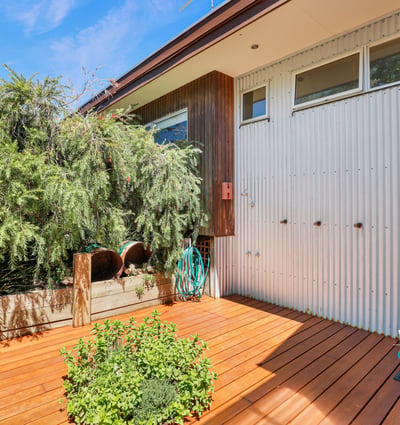 Bright and inviting outdoor space featuring a wooden deck, unique architectural details, and lush greenery.