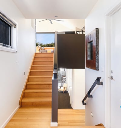 Bright entryway with modern design, featuring warm wood accents and an inviting staircase leading to open spaces.