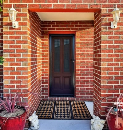 Discover a welcoming entryway framed by vibrant greenery and warm brick accents, perfect for inviting guests.