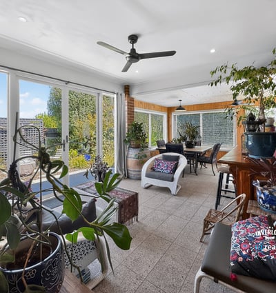 Bright and inviting sunroom with abundant greenery, perfect for relaxation and entertaining year-round.