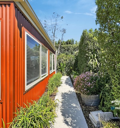 Lush landscaping surrounds this vibrant home, featuring a welcoming pathway and abundant greenery for outdoor enjoyment.