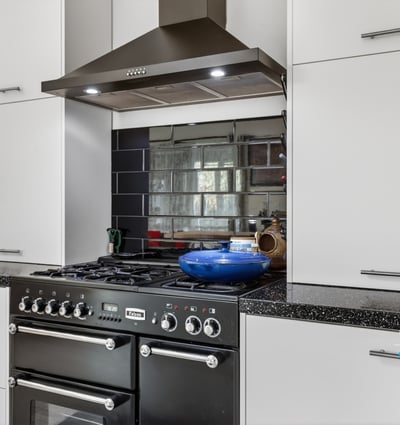Modern kitchen featuring sleek cabinetry, a gas range, and a striking mirrored backsplash for added depth.