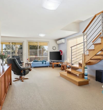 Bright and spacious living area with modern furnishings, featuring a staircase and natural light throughout.