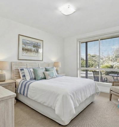 Bright and inviting bedroom featuring large windows, comfortable furnishings, and a relaxing atmosphere.