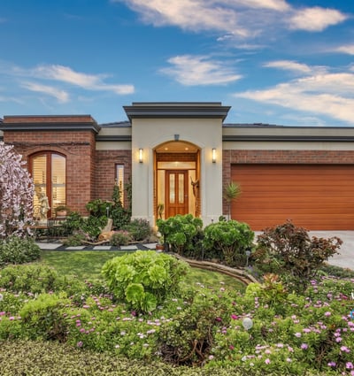 This inviting home features vibrant landscaping, a spacious garage, and a welcoming entryway.