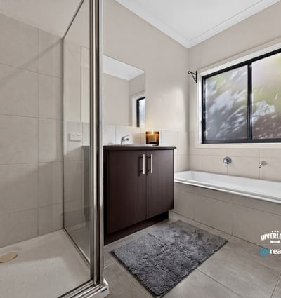 Modern bathroom featuring a spacious shower, separate tub, and large window for natural light.