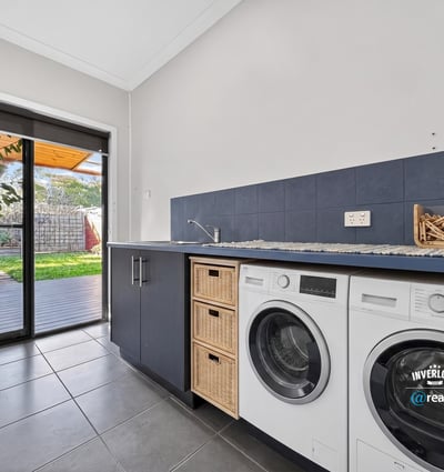 Bright laundry room featuring modern appliances and direct access to a shaded outdoor area.