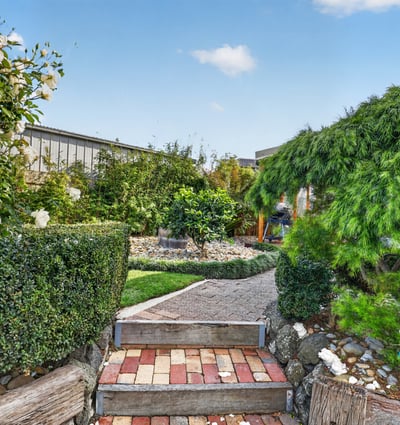 Discover a beautifully landscaped garden pathway surrounded by lush greenery and vibrant plant life.