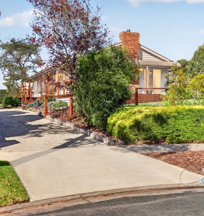 This spacious home features a picturesque landscape, inviting driveway, and ample outdoor space for entertaining.