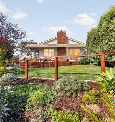Discover a beautifully landscaped property featuring a spacious backyard with vibrant greenery and ample outdoor space.