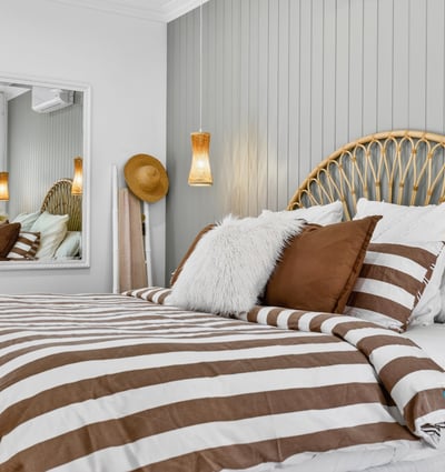 Cozy bedroom featuring a unique headboard, striped bedding, and modern accents for a relaxed atmosphere.