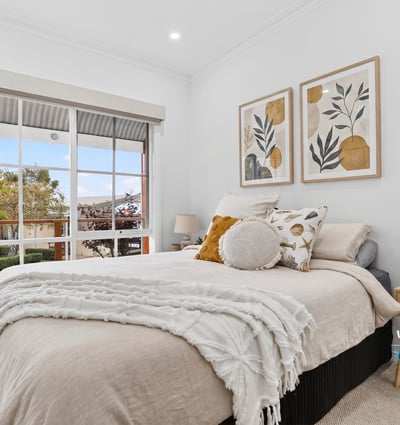 Bright and inviting bedroom featuring large windows, modern decor, and a cozy atmosphere for relaxation.