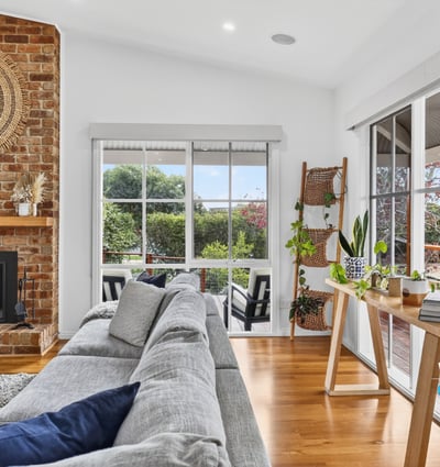 Bright, inviting living space featuring a cozy fireplace and panoramic views of the surrounding gardens.