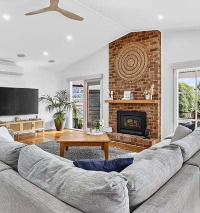 Spacious living area features a cozy fireplace, ample natural light, and direct access to outdoor views.
