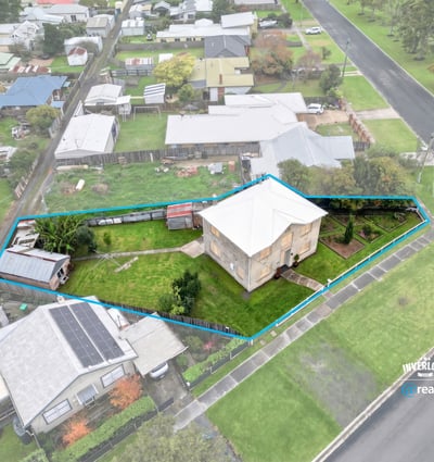 Spacious corner lot with potential for development, featuring a two-story home and ample outdoor space.