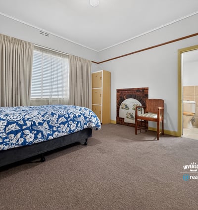 Spacious bedroom featuring natural light, a cozy seating area, and convenient access to an ensuite bathroom.