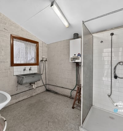 Spacious bathroom featuring a modern shower, practical sink area, and ample natural light.