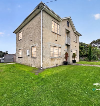 Spacious multi-level property on a generous lot, featuring large windows and expansive green yard.