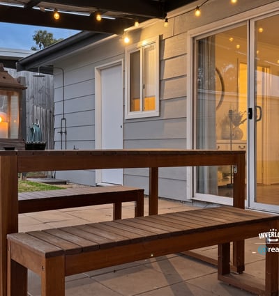 This inviting outdoor space features a wooden dining set and soft lighting, perfect for gatherings.
