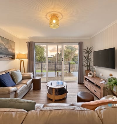 Bright living room with modern furnishings, large window views, and seamless access to an outdoor deck.