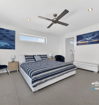 Light-filled bedroom featuring modern decor, ample space, and beautiful ocean-themed artwork for a refreshing atmosphere.
