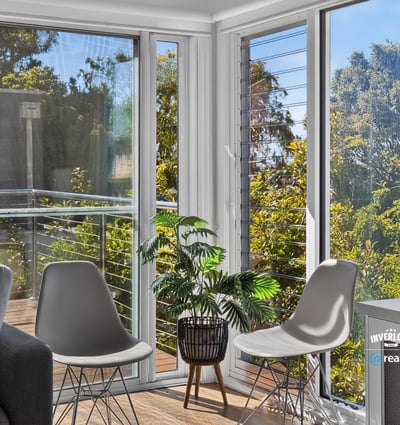 Bright and airy living space featuring large windows and a balcony with lush outdoor views.