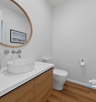 Bright and modern bathroom featuring a unique round mirror and sleek wood cabinetry for functional appeal.