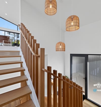 Bright and airy entryway featuring modern lighting and open staircase, seamlessly connecting indoor and outdoor spaces.