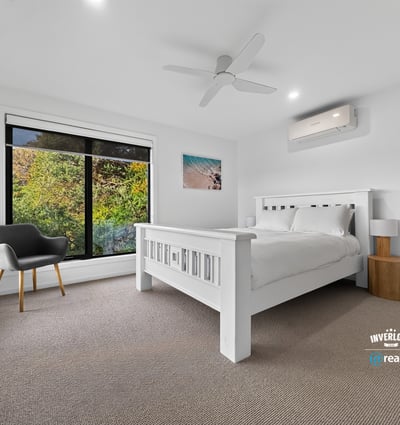 Bright bedroom with large windows showcasing natural light and leafy views, featuring modern finishes and comfort.