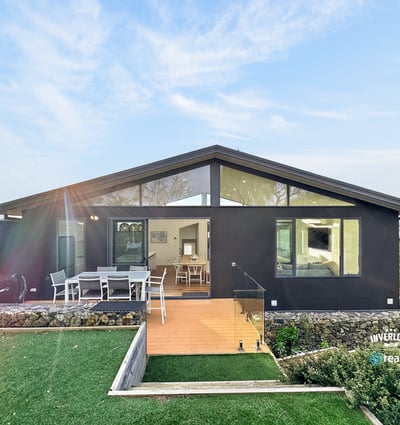 Contemporary home featuring expansive windows and a spacious outdoor deck, perfect for entertaining and relaxation.