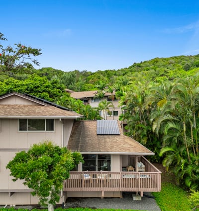 Nestled among lush greenery, this spacious home features a large deck and modern solar energy system.