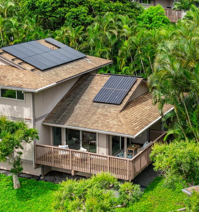 Discover this modern home featuring solar panels and a spacious deck, surrounded by lush tropical landscaping.