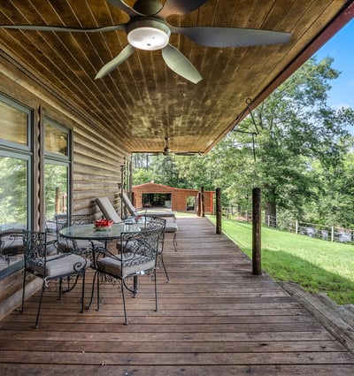 Spacious covered porch with ample seating, perfect for enjoying panoramic views of the surrounding landscape.